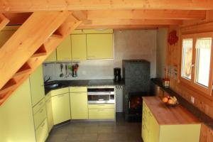 una cocina con armarios amarillos y una escalera de madera en La Casa Cathomen Brigels - Maiensäss/Berghaus für max. 6 Personen en Brigels