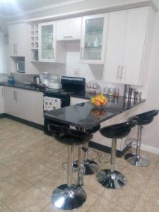 a kitchen with a table and bar stools at Sheilas home away from home in Lusaka
