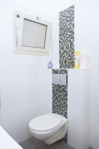 bagno bianco con servizi igienici e specchio di Apartments4you Bally a Bat Yam