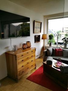 a living room with a wooden dresser and a couch at LUXURIÖSE FERIENWOHNUNG CONFLUENTIA IN DER KOBLENZER ALTSTADT in Koblenz