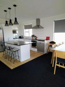 a kitchen with white cabinets and a table with chairs at Modern House near Motuoapa Tongariro Crossing fishing skiing in Turangi