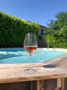 a glass of wine sitting on a table next to a swimming pool at La petite maison en pierres in Gras