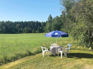 una mesa y sillas bajo una sombrilla en un campo en 6 person holiday home in VARA, en Skår