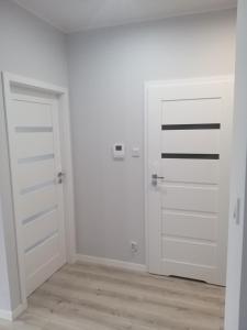 um quarto vazio com duas portas brancas e pisos de madeira em Apartament Nowa Letnica em Gdansk