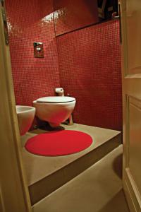 łazienka z toaletą i czerwoną ścianą wyłożoną kafelkami w obiekcie I Mulini B&B w mieście Vigevano