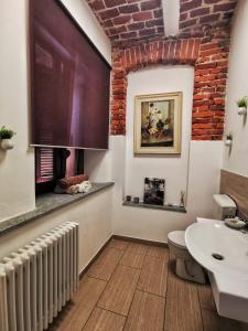 La salle de bains est pourvue d'un lavabo blanc et d'un mur en briques. dans l'établissement Regis B&B Camere centro storico, à Chivasso