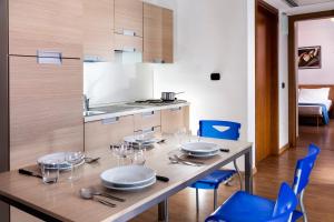 une salle à manger avec une table en bois et des chaises bleues dans l'établissement Aparthotel Esperya, à Lignano Sabbiadoro