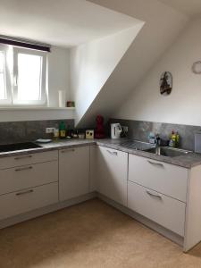 a kitchen with white cabinets and a sink and a window at Ferienwohnung Pfeifer 2 in Friedrichsdorf