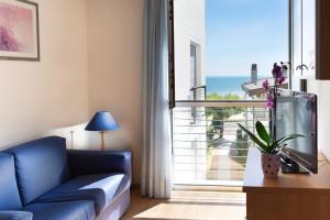 a living room with a blue couch and a large window at Aparthotel Esperya in Lignano Sabbiadoro