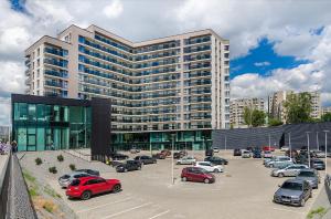 a large building with cars parked in a parking lot at Bright apartment near Akropolis in Vilnius