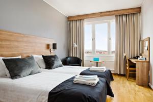 a hotel room with two beds and a desk at Quality Hotel Bodensia in Boden