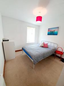 a bedroom with a bed and a red chair at Southend Ground Floor Apartment with Parking in Southend-on-Sea