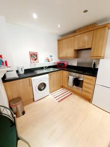 a kitchen with wooden cabinets and a washer and dryer at Southend Ground Floor Apartment with Parking in Southend-on-Sea