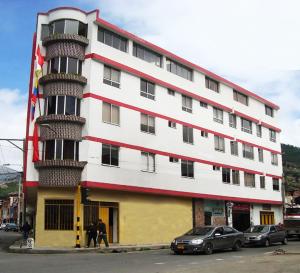 een groot wit en rood gebouw met auto's buiten geparkeerd bij Hotel Dancar in Pamplona