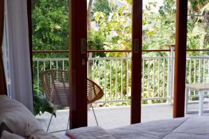 ein Schlafzimmer mit einer Tür, die auf eine Veranda mit einem Stuhl führt in der Unterkunft The Sloth Bali in Canggu
