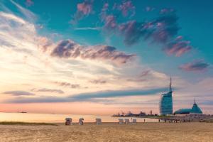 une plage avec des chaises et un bâtiment au loin dans l'établissement Ferienwohnungen an der Weser, à Bremerhaven