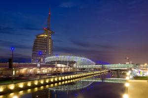 eine Stadt in der Nacht mit einem Gebäude und einer Brücke in der Unterkunft Ferienwohnungen an der Weser in Bremerhaven