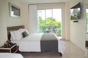 a hotel room with two beds and a balcony at Hotel Metropolitano Plaza in Valledupar