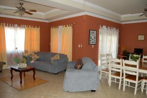a living room with two couches and a table at Casa del Sol Tobago in Bon Accord Village