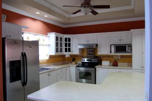 a kitchen with white cabinets and a ceiling fan at Casa del Sol Tobago in Bon Accord Village