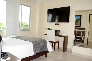 a bedroom with a bed and a desk and a tv at Hotel Metropolitano Plaza in Valledupar