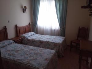 a hotel room with two beds and a window at Hotel Rural Puerta de Caderechas in Terminón