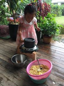 a little girl standing next to a bowl of food at 桐庐舍予民宿 Tonglu Sheyu Country House in Tonglu