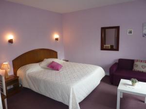 a bedroom with a bed and a purple couch at Hôtel A La Renommée in Saint-Père