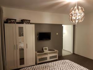 a bedroom with a bed and a tv and a chandelier at Marcos Apartments - self check-in in Reşiţa