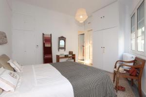 a white bedroom with a bed and a chair at Plaka penthouse with Acropolis views! - PL6 in Athens