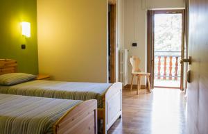 a bedroom with two beds and a door to a balcony at Albergo Ristorante Cuccini in San Domenico