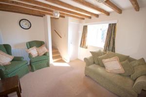 een woonkamer met een bank en stoelen en een klok bij Wish Cottage in Ratton Village