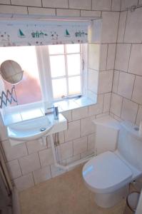 een badkamer met een toilet, een wastafel en een raam bij Wish Cottage in Ratton Village