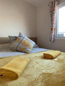 1 cama con 2 toallas y ventana en Brambles 66 -Static Holiday Caravan, Porthcawl, en Newton