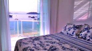 a bedroom with a bed with a view of the ocean at Apto Praia Grande - Angra dos Reis in Angra dos Reis +27 photos