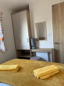 sypialnia z łóżkiem z dwoma żółtymi ręcznikami w obiekcie Brambles 66 -Static Holiday Caravan, Porthcawl w mieście Newton