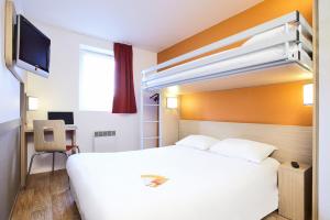 ein Hotelzimmer mit einem weißen Bett und einem TV in der Unterkunft Première Classe Lyon Sud - Pierre Bénite in Irigny