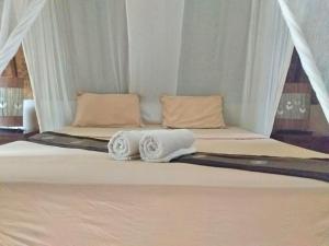 Una cama con dos toallas encima. en Colour Cottage, en Gili Air