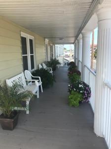 a porch with white chairs and flowers on a house at The Admiral Hotel/Motel in Ocean City