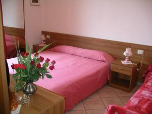 Un dormitorio con una cama rosa y una mesa con flores en Affittacamere La Rosa, en Lucca 11 fotos más