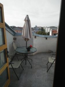 una mesa y sillas con una sombrilla en el balcón en Garsoniera langa plaja en Constanza