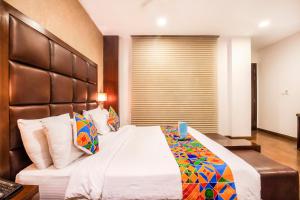 a hotel room with a bed, chair, and nightstand at FabHotel Jasmine Boutique Jasola - Fully Vaccinated Staff in New Delhi