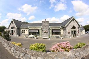a stone building with a stone fence in front of it at Auburn Lodge Hotel & Leisure Centre in Ennis