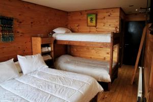 2 literas en una habitación con paredes de madera en Ruka Antu Ecolodge en Cobquecura