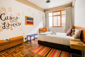 a room with a bed, a desk and a painting on the wall at Selina Plaza De Armas Cusco in Cusco