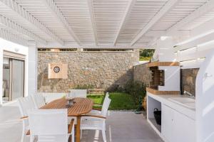 a kitchen and dining room with a wooden table and white chairs at Villa Sea La Vie in Kiotari