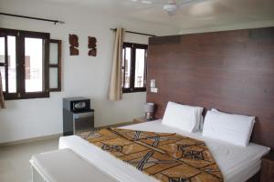 Schlafzimmer mit einem großen Bett mit einem Kopfteil aus Holz in der Unterkunft Harmony Resort Boutique Hotel in Banjul