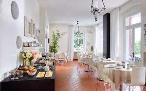 uma sala de jantar com mesas brancas e cadeiras brancas em Albergo Garnì Villa Moretti em Riva del Garda