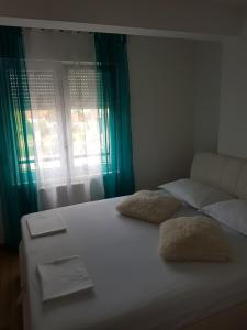 a white bed with two pillows on it with a window at Apartman DIJANA in Banja Luka