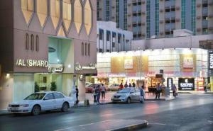 een stadsstraat met auto's geparkeerd voor gebouwen bij Al Sharq Hotel - BAITHANS in Sharjah